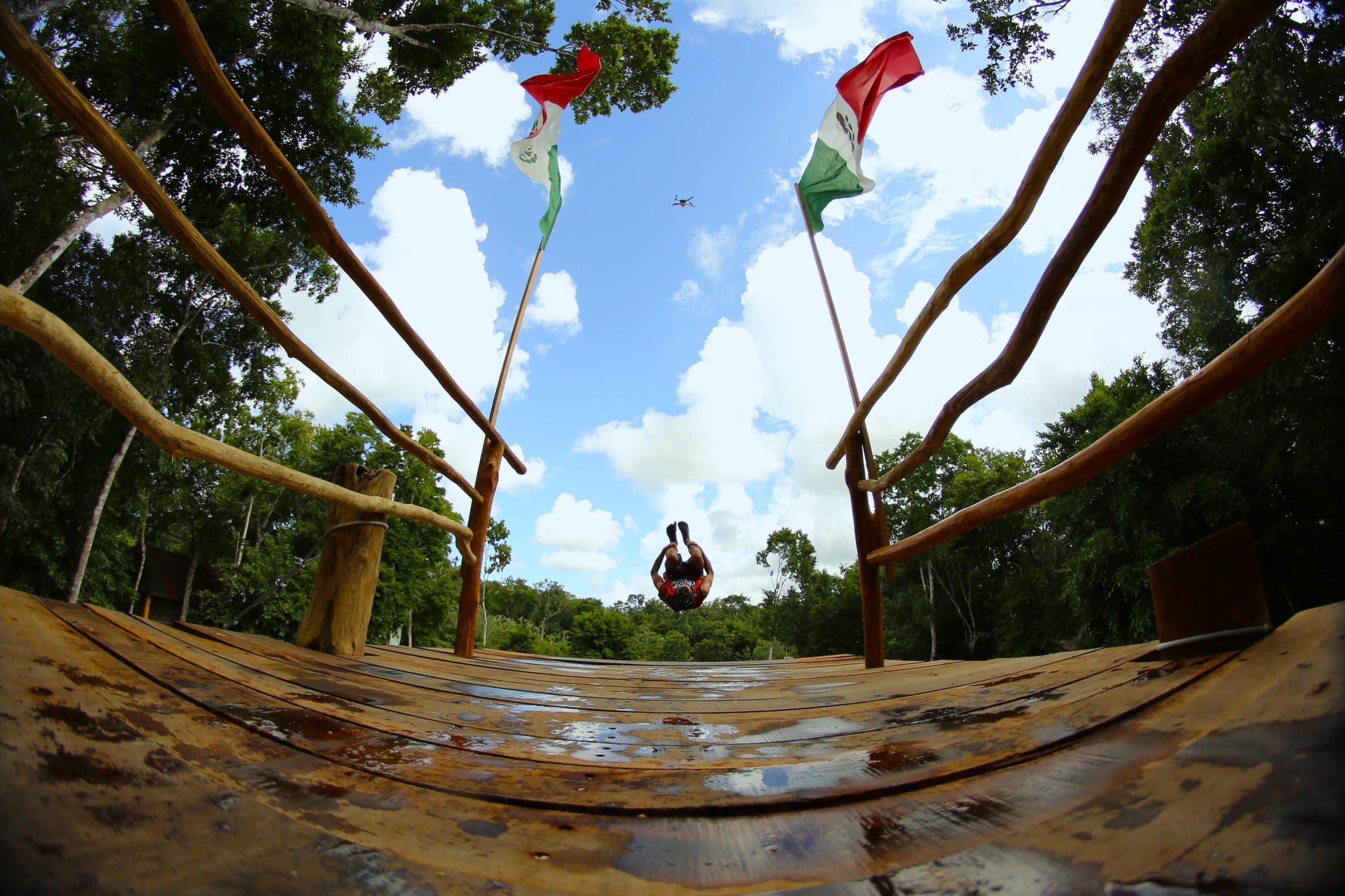A jumper backflips off the top of the jumping tower between two Mexican flags